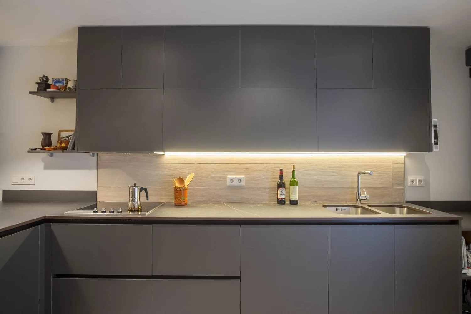 Frente de cocina en gris grafito con encimera de piedra, salpicadero de madera e iluminación LED