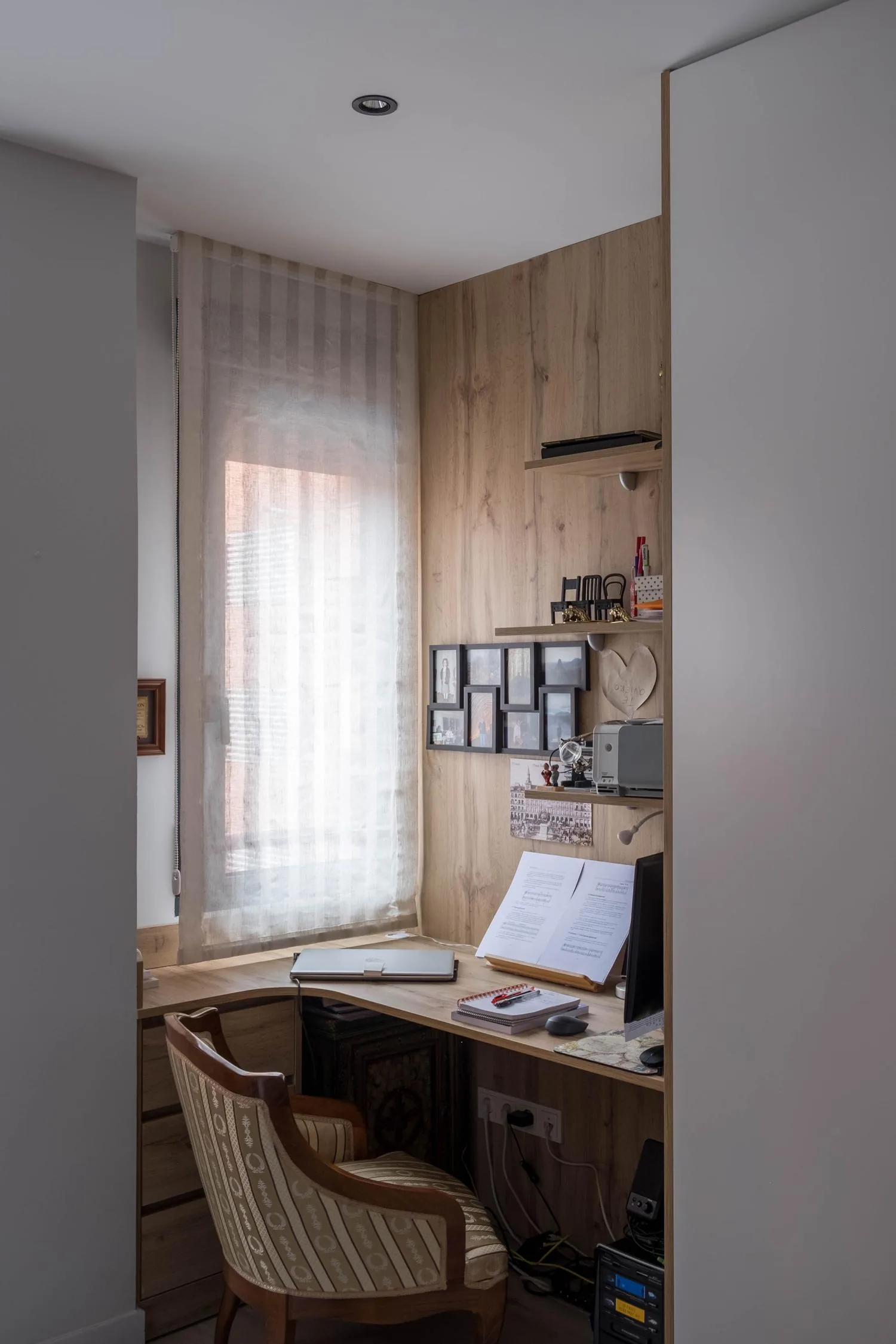 Rincón de trabajo a medida en el dormitorio, con escritorio y estantes de madera junto a la ventana
