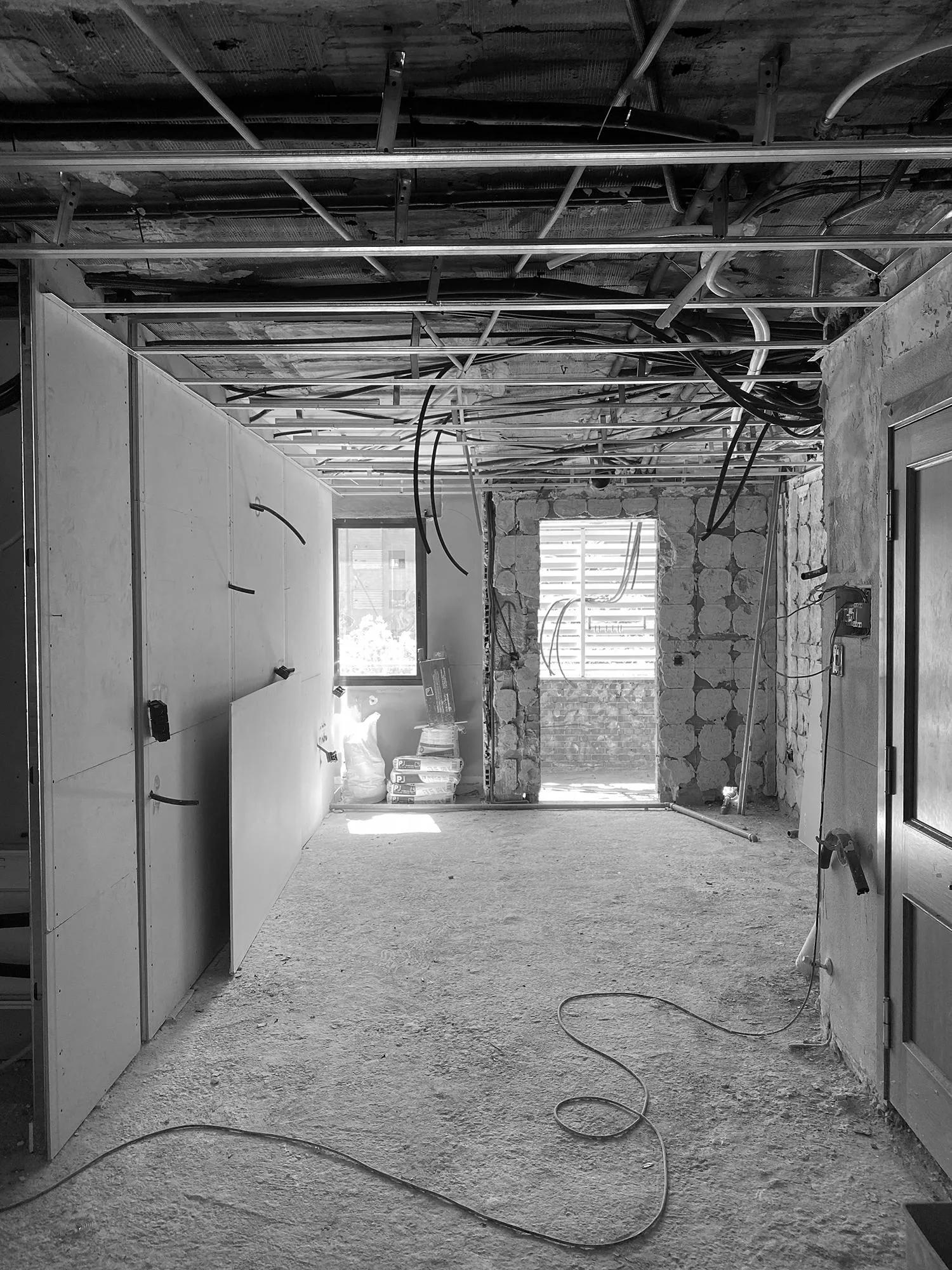 Vivienda durante la obra, con el techo desmontado, instalaciones vistas y muros de piedra al descubierto