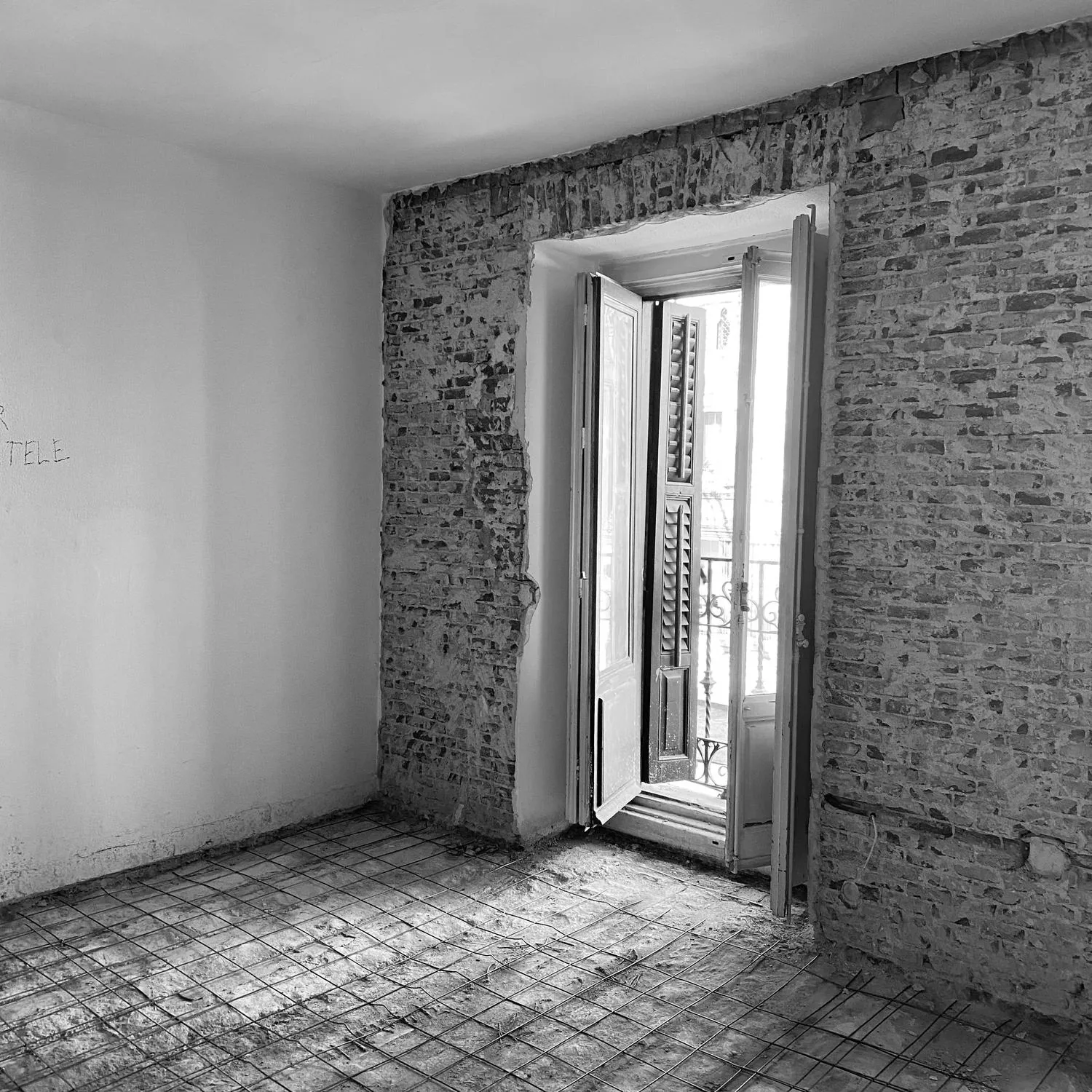 Reforma integral en obra: salón de un piso antiguo de Madrid con el ladrillo visto y el suelo al descubierto