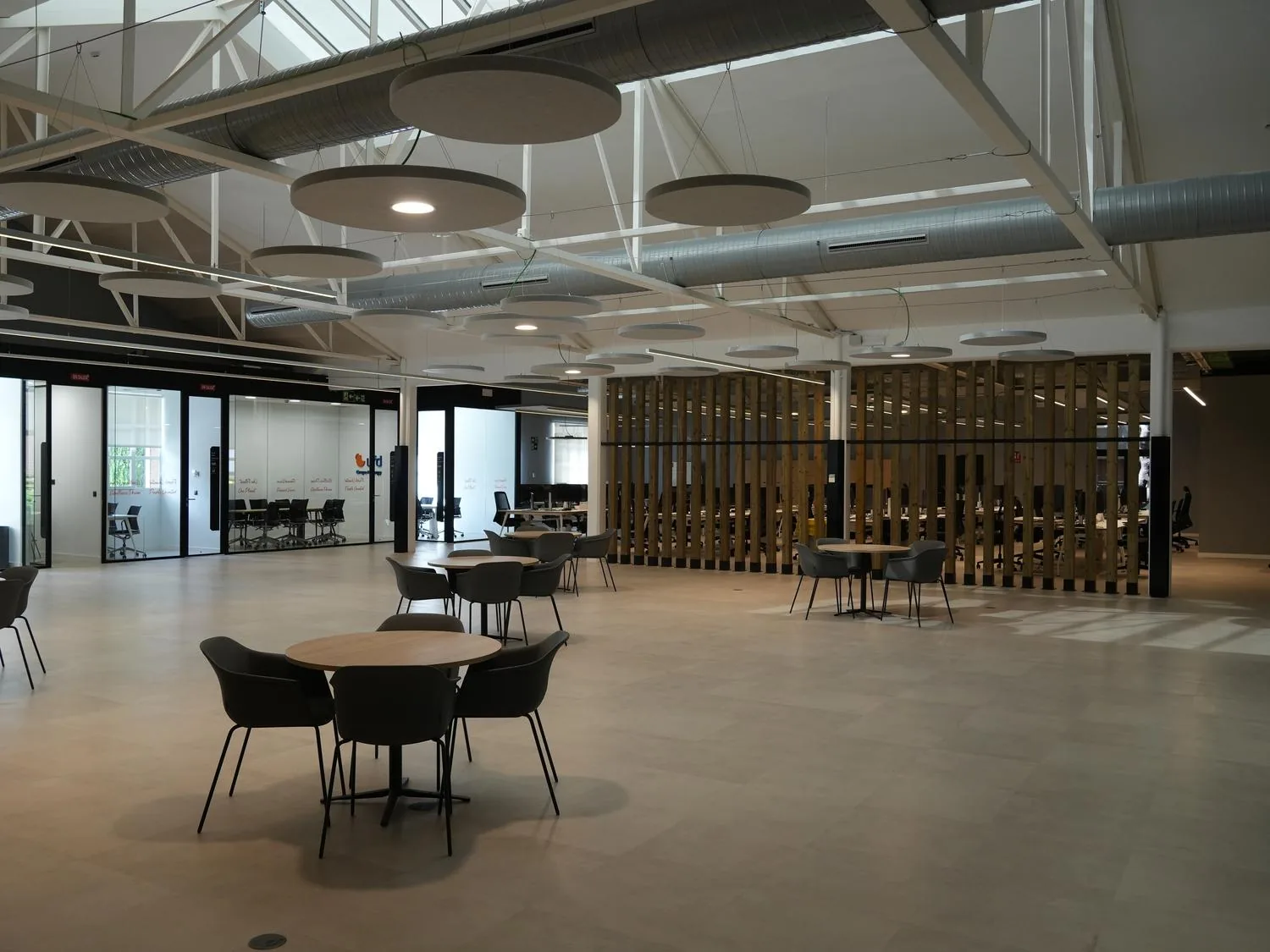 Reforma de oficinas de UFD Naturgy en Madrid: zona de reuniones informales con cerchas vistas y paneles acústicos circulares