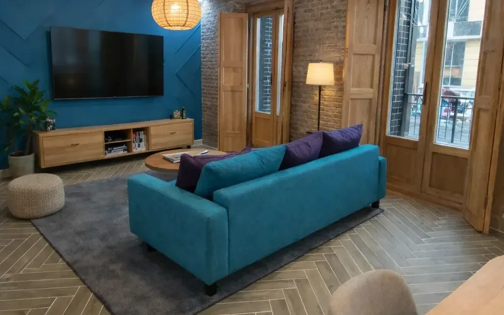 Salón del piso T49, con sofá turquesa, pared azul y carpinterías de madera restauradas