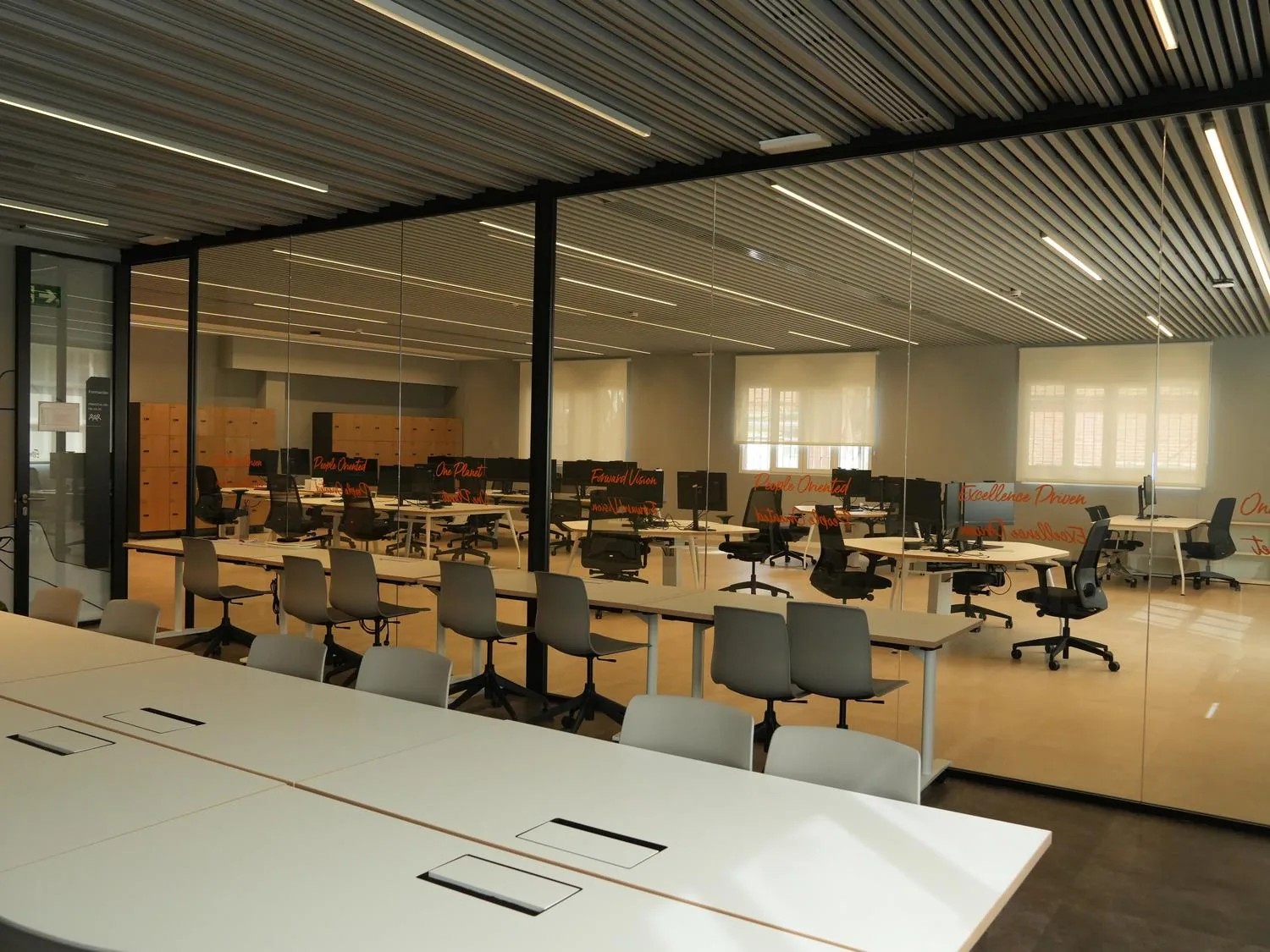 Aula de formación y zona de trabajo, con tabiques de vidrio y techo de lamas de madera