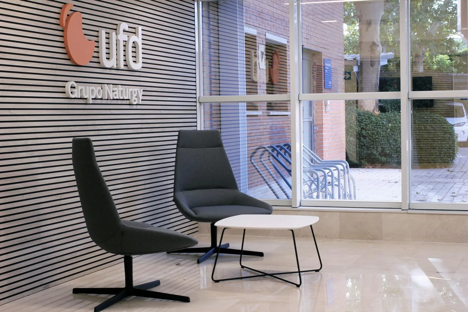 Recepción reformada de UFD Naturgy, con el logo corporativo sobre pared de lama