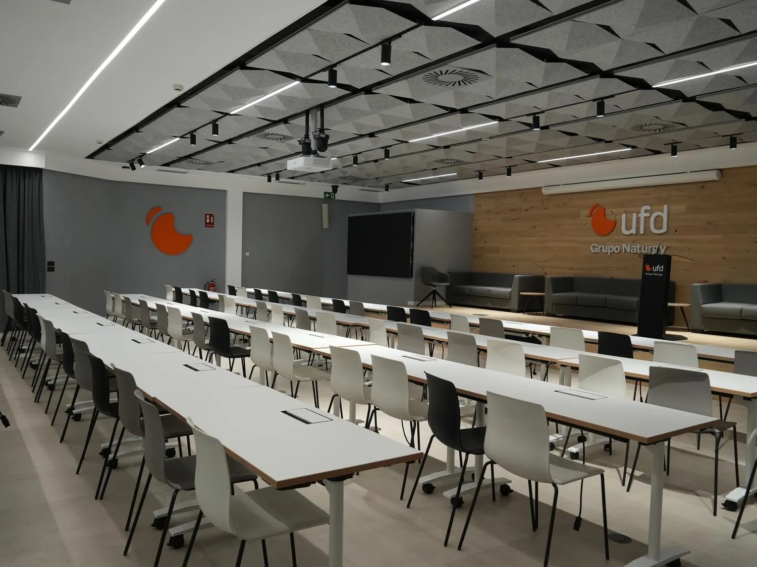 Sala multifuncional para formación y eventos, con el logo corporativo y muro de ladrillo visto